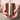 Close-up of two hands holding a polished copper-plated Sojourn Calm Ritual Scented Candle vessel, reflecting warm light and evoking a calm, luxurious ritual moment.