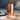 Sojourn Calm Your Mind Candle Mood Image: Copper‑plated Sojourn candle placed on a light wooden surface beside a monochrome magazine cover, set within a soft, cozy living‑room scene that evokes calmness and warmth.