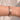 Close up of wrist wearing a Sojourn Nourish Wide Copper Cuff, hand engraved design with stars and moons, against a sunlit background.